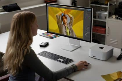 A person is using an Apple computer at a desk with a monitor, keyboard, and mouse.