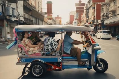 A tuk-tuk driving through a busy Thai street, showcasing vibrant local culture.