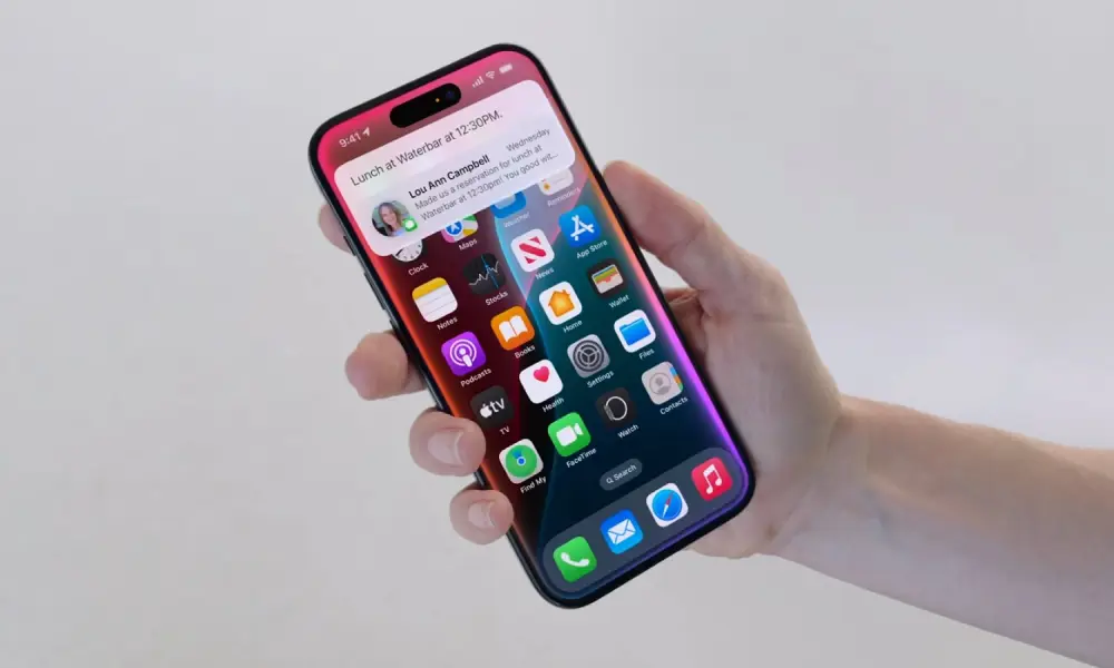 Hand holding an iPhone displaying iOS 18.1.