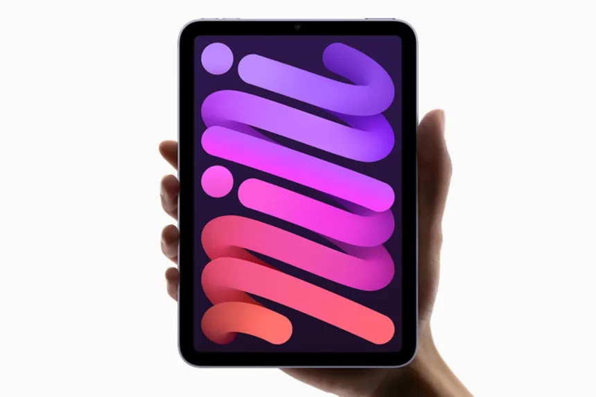 A hand holds an iPad Mini with a colorful design on the screen.