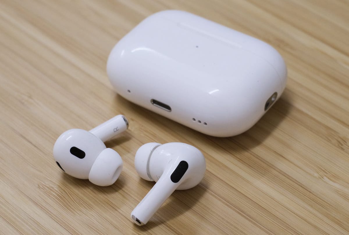 Apple AirPods Pro 2 with charging case on a wooden surface.