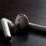 Close-up of two Apple AirPods on a dark surface.