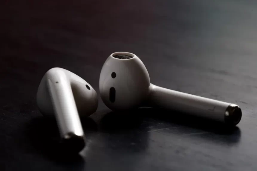 Close-up of two Apple AirPods on a dark surface.