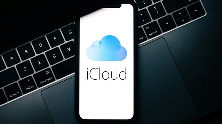 iPhone showing iCloud logo placed on a MacBook keyboard.