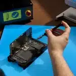 Person repairing an iPhone using tools on a workbench.