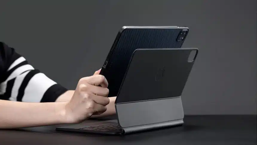 Person holding an iPad attached to a Magic Keyboard.