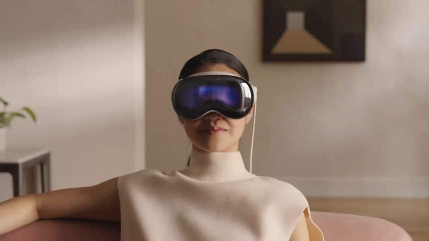 A person wearing Apple Vision Pro headset sitting indoors.