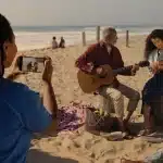 Person recording a beach scene with a smartphone.