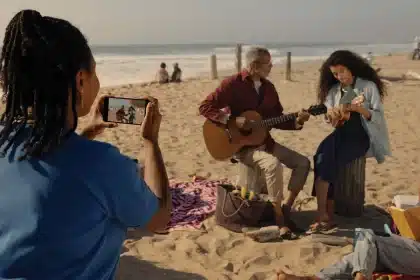 Person recording a beach scene with a smartphone.