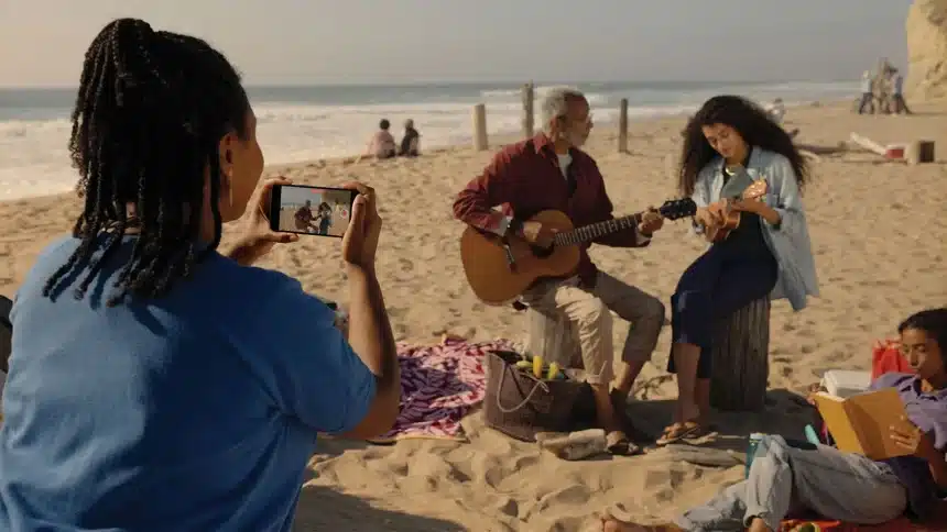 Person recording a beach scene with a smartphone.