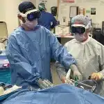 Surgeons wearing Apple Vision Pro headsets during a procedure.