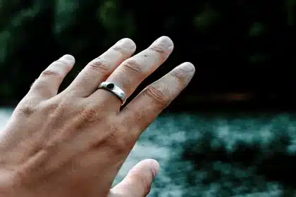 Hand wearing a smart ring near water.