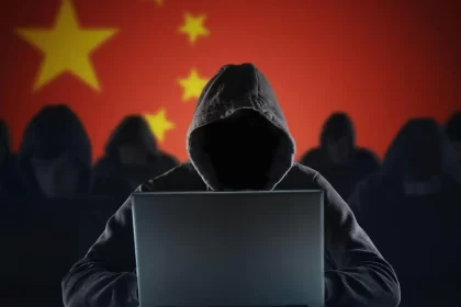 Hacker with laptop in front of Chinese flag.