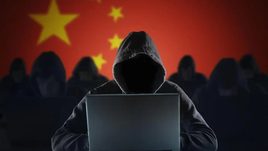 Hacker with laptop in front of Chinese flag.