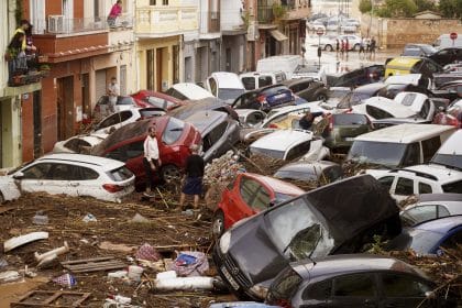 Flood damage with cars piled up and debris scattered in a Valencia street.