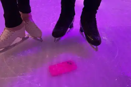 Skaters on ice with a pink iPhone frozen beneath the surface.