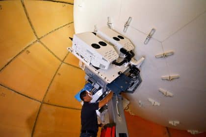 Technician working on a satellite installation inside a large dome.