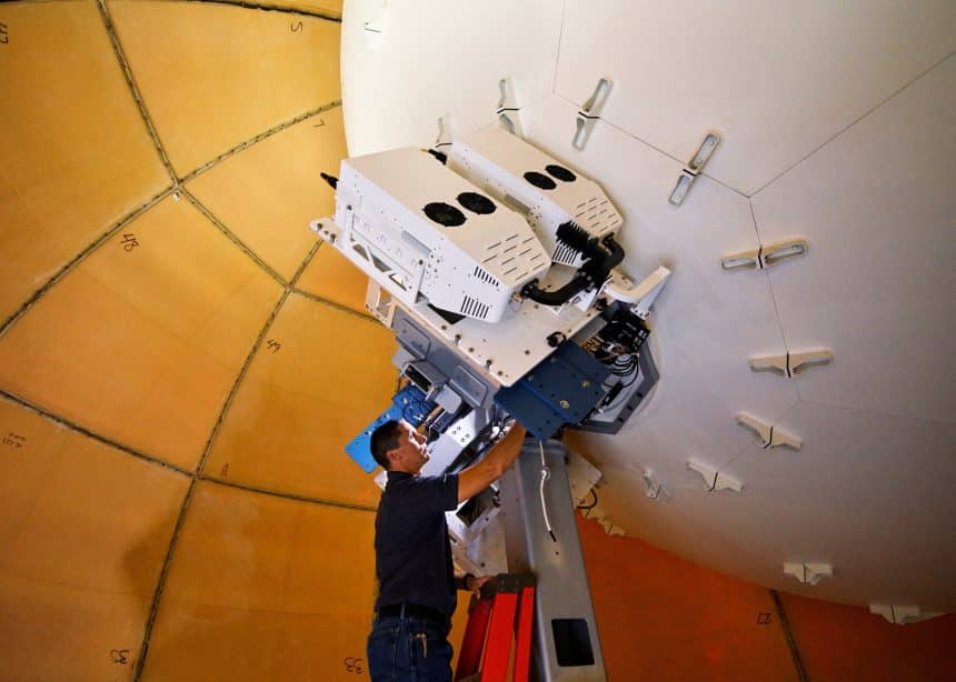 Technician working on a satellite installation inside a large dome.