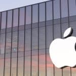 Apple logo on a glass building at sunset.