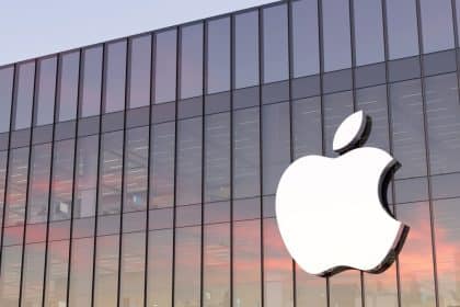 Apple logo on a glass building at sunset.