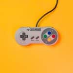 Super Nintendo controller on a bright yellow background.