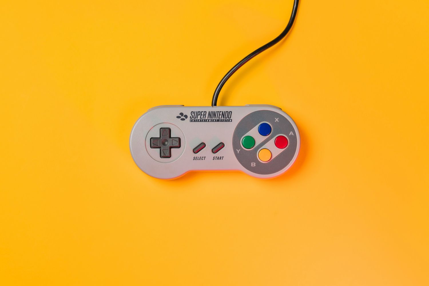 Super Nintendo controller on a bright yellow background.