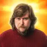 Man in red sweater with sunburst background.