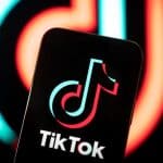 Smartphone displaying the TikTok logo with a blurred TikTok background.