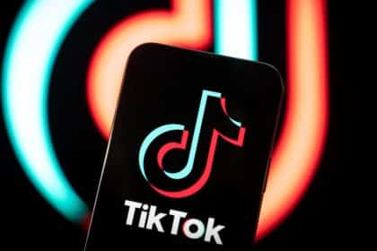 Smartphone displaying the TikTok logo with a blurred TikTok background.