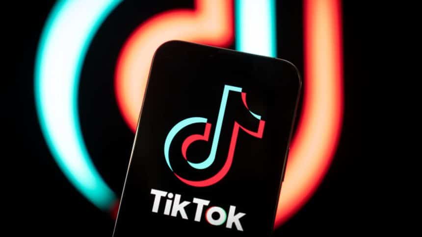 Smartphone displaying the TikTok logo with a blurred TikTok background.