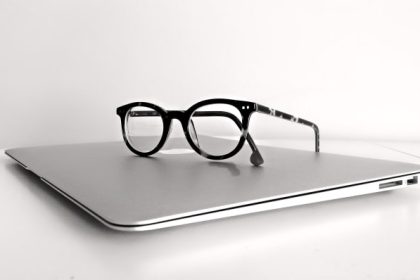 Black-framed glasses resting on a closed silver laptop