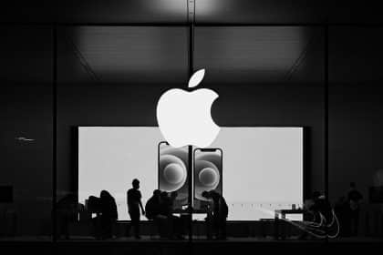 Apple Store with illuminated logo and customers inside.