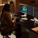 A person working on a Mac Studio with dual monitors in a modern office setup.