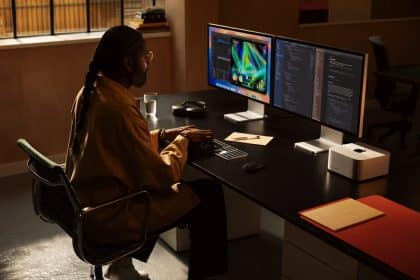 A person working on a Mac Studio with dual monitors in a modern office setup.