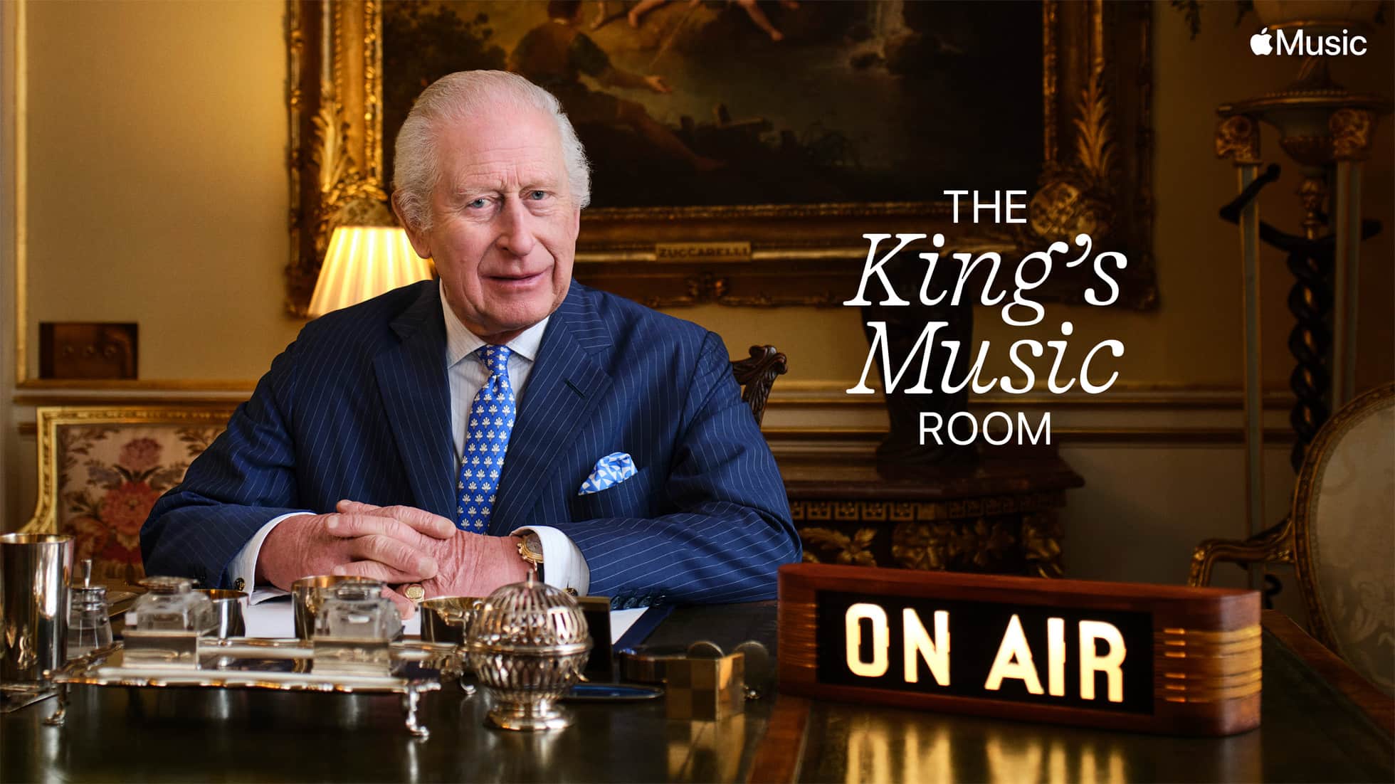 King Charles III hosting The King's Music Room on Apple Music 1, with an "On Air" sign in front of him.