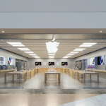 Apple Store in France with a glass storefront and illuminated Apple logo.