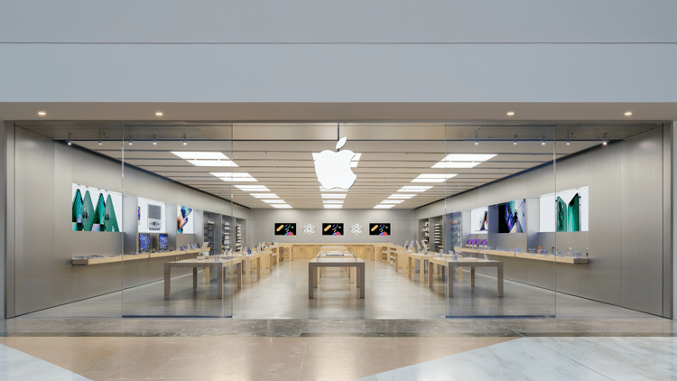 Apple Store in France with a glass storefront and illuminated Apple logo.