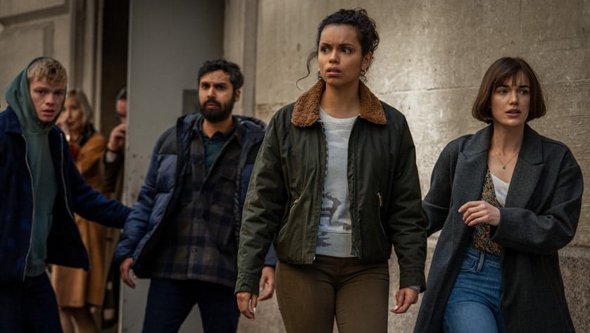 A group of four people looking tense and alert in an urban setting.