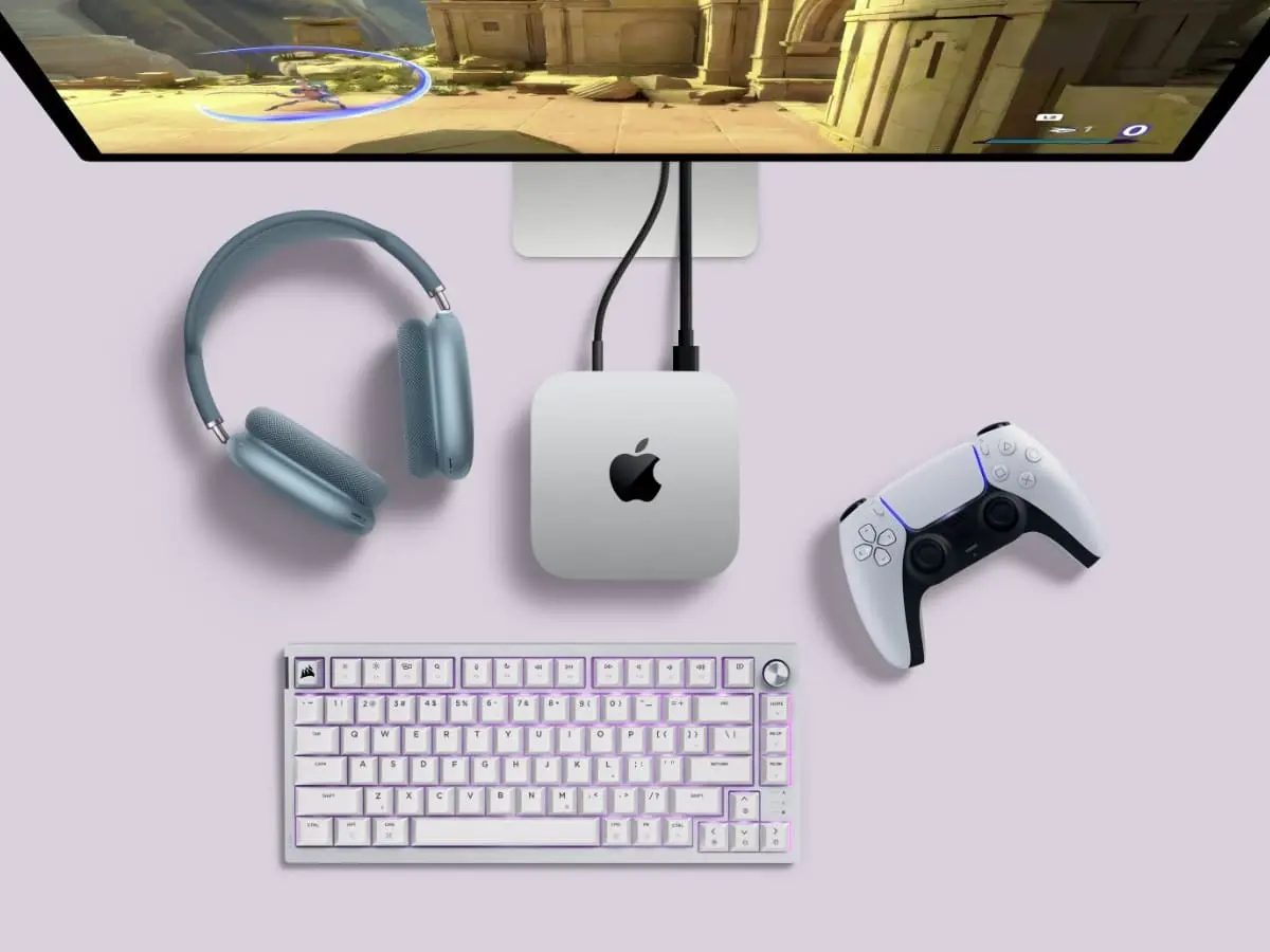 Apple Mac Mini setup with a gaming monitor, headphones, keyboard, and PlayStation controller.